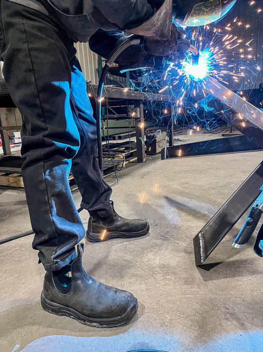 Someone wearing a pair of 163 black CSA steel toe boots while welding.