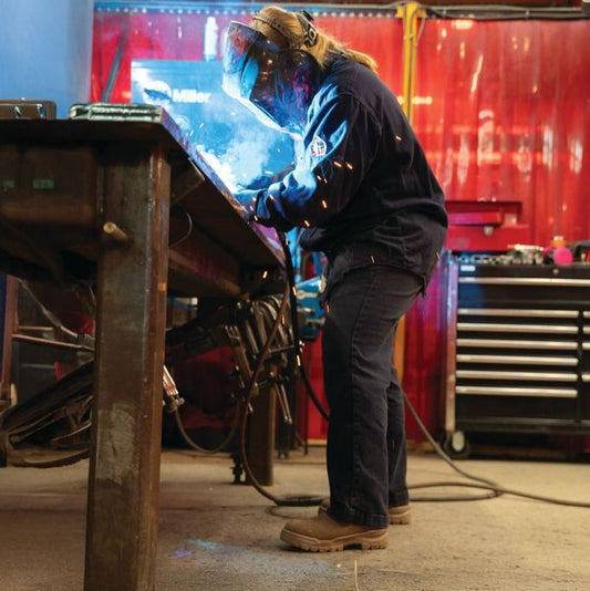 A person wearing the new composite rotoflex CSA blundstones while welding in a workshop in the stone colour.