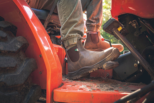Pair of 180 CSA Blundstones in rustic brown worn on a tractor.